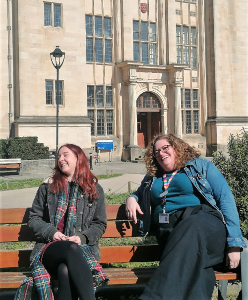 Rosey and Victoria sitting on a bench laughing.